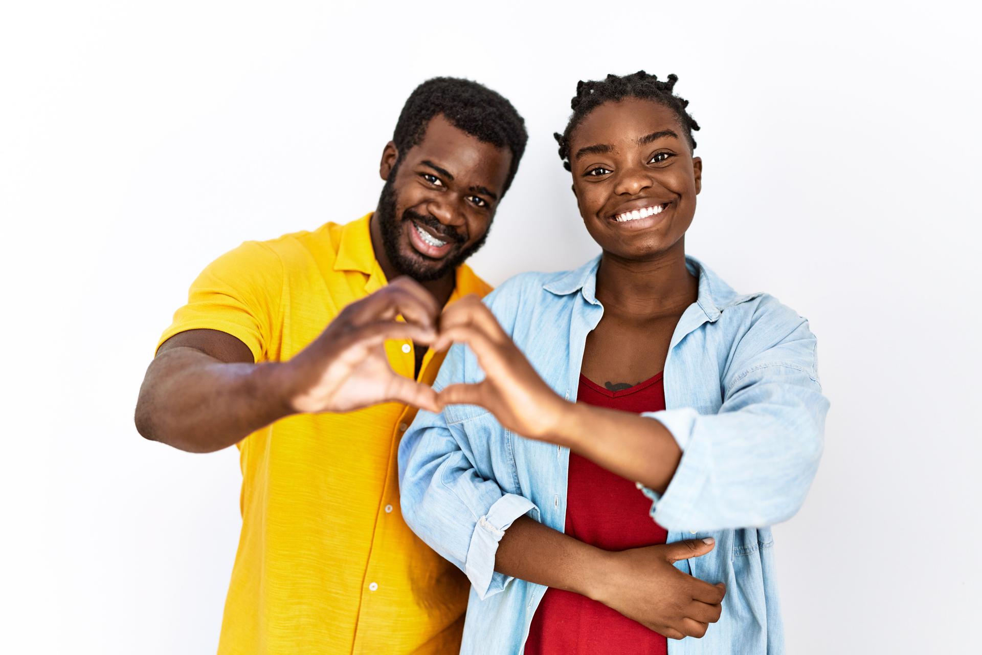 Young african american couple wearing casual clothes smiling in love doing heart symbol shape with hands. romantic concept.