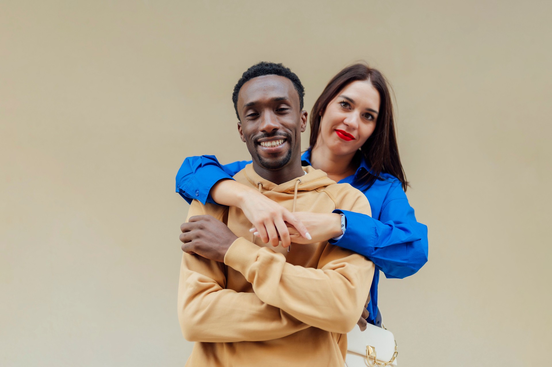 Portrait of a happy interracial couple in casual clothes on a yellow background in the studio. Young brunette of European appearance hugs her African American boyfriend