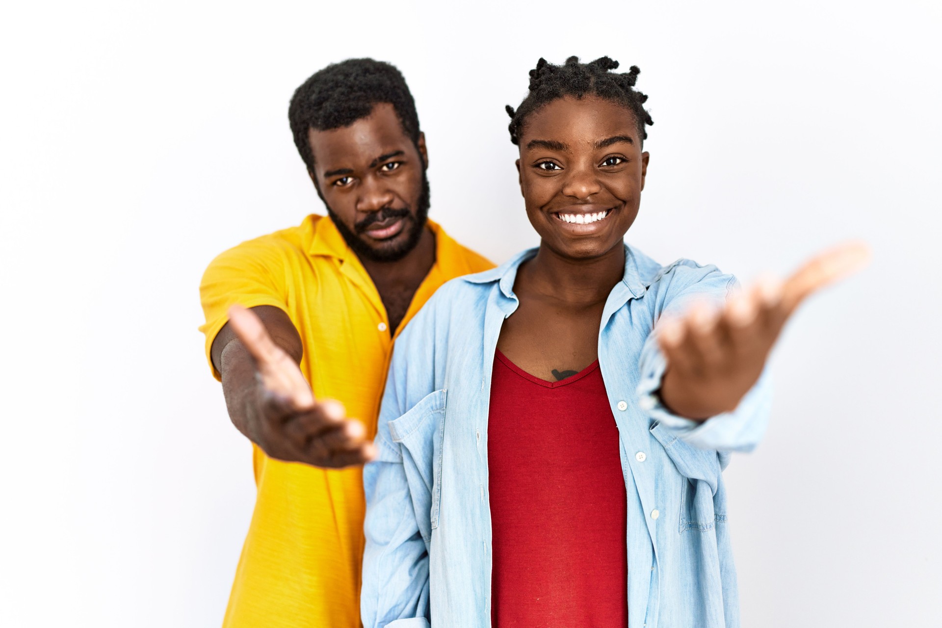 Young african american couple wearing casual clothes smiling friendly offering handshake as greeting and welcoming. successful business.